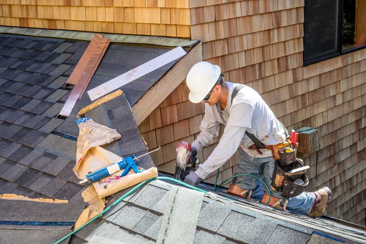 Installing new roof with nail gun and shingles