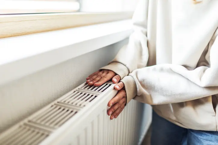 Woman warms up hands over heater